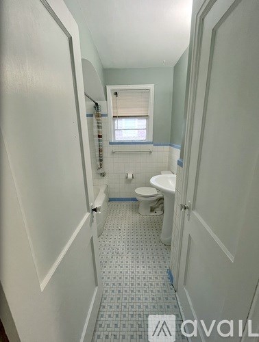 A bathroom with a toilet, sink, and a window.