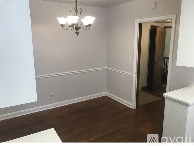 A room with a chandelier and wood flooring.