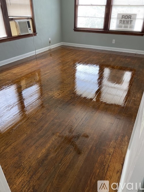 A room with wooden floors and a window with blinds.
