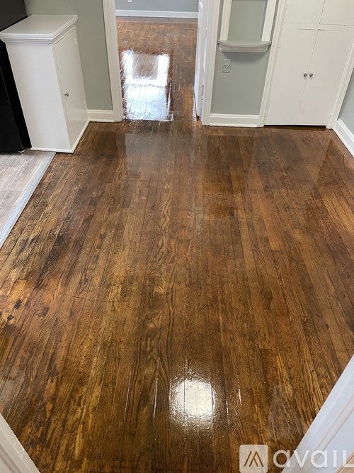 A room with a wooden floor and white cupboards.
