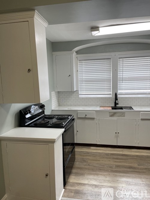 A kitchen with a black stove top oven and white cabinets.