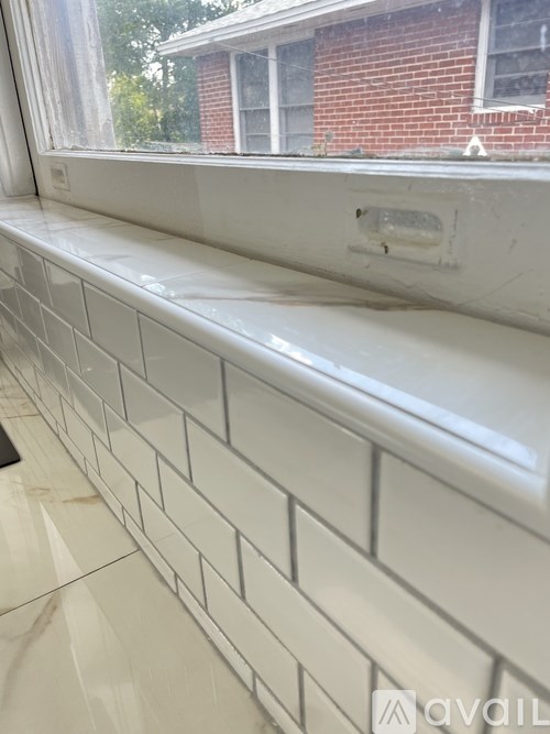 A white tiled wall next to a window.