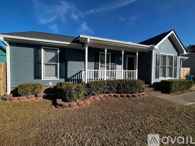 A blue house with a white porch and a small front yard.