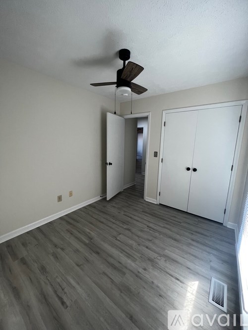 A room with a ceiling fan and a wooden floor.