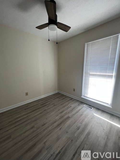 A room with a ceiling fan and a window with blinds.