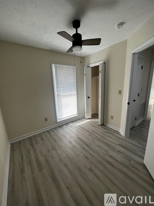 A room with a ceiling fan and wooden flooring.
