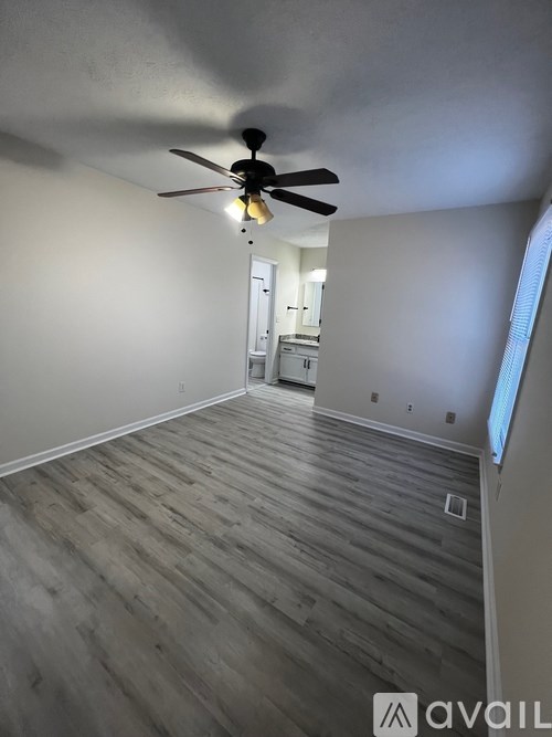A room with a ceiling fan and wooden flooring.