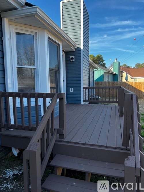 A wooden deck with a railing and steps leading to a house.
