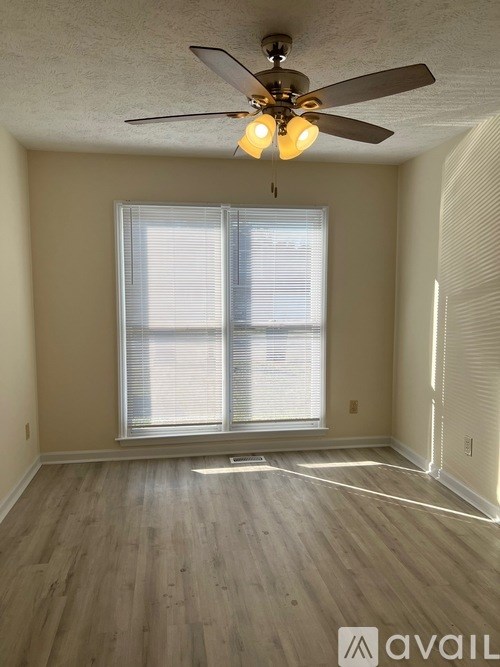 A room with a ceiling fan and a window with blinds.