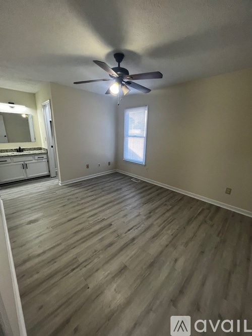 A room with a ceiling fan and wooden flooring.