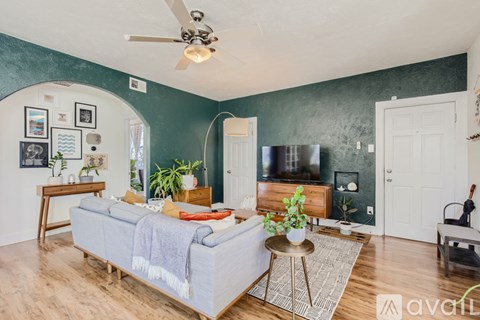 A living room with a grey couch and a ceiling fan.