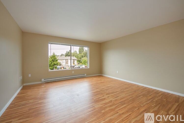Empty room with wooden flooring and a large window.