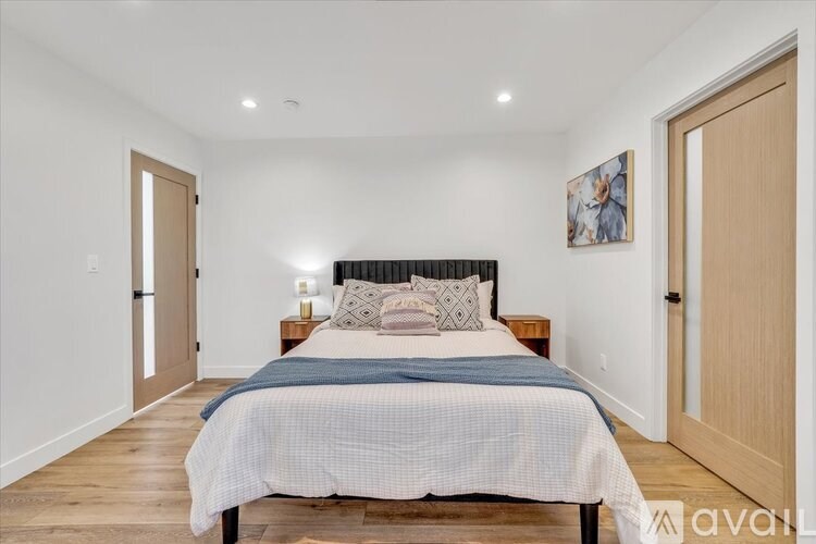 A bedroom with a bed, nightstands, and a painting on the wall.