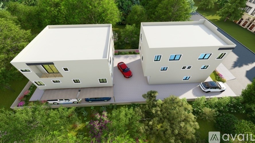 Two white houses with a red car parked in front of them.