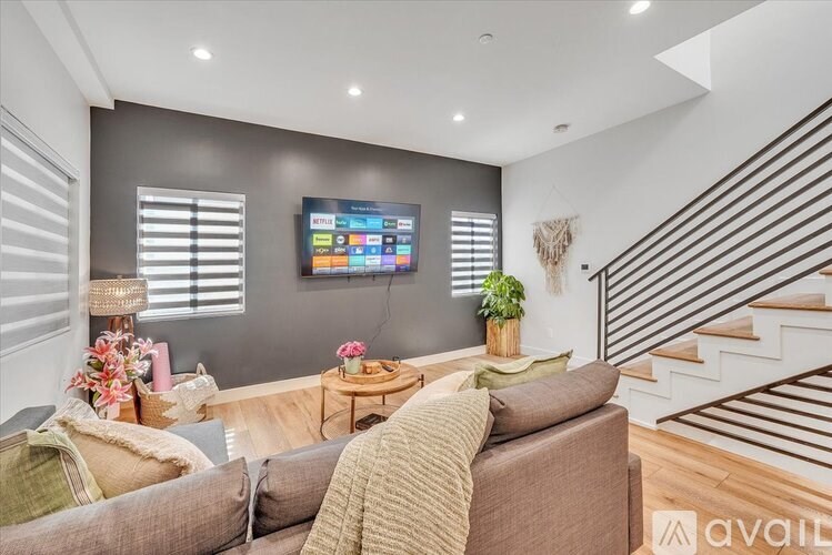 A living room with a couch, a coffee table, and a television mounted on the wall.