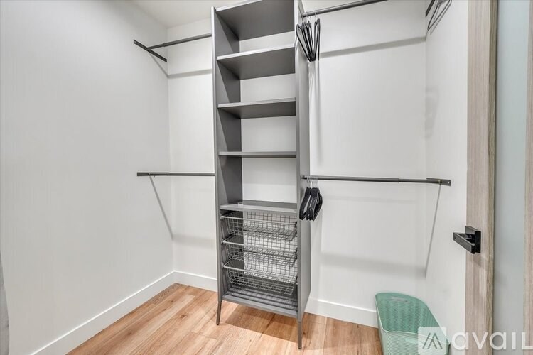 A white wall with a shelving unit and a green trash can.