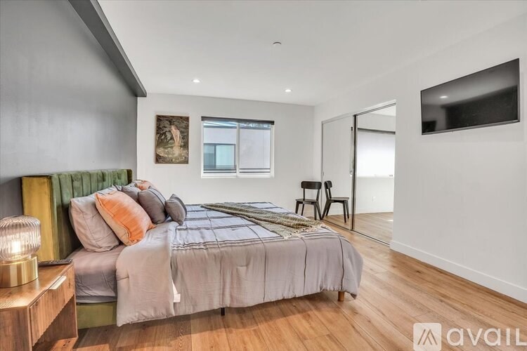 A bedroom with a bed, a chair, and a painting on the wall.