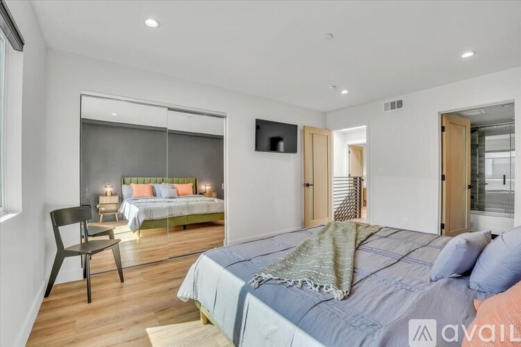 A bedroom with a bed, chair, and a window.