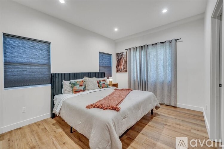 A bedroom with a bed, pillows, and a window with curtains.