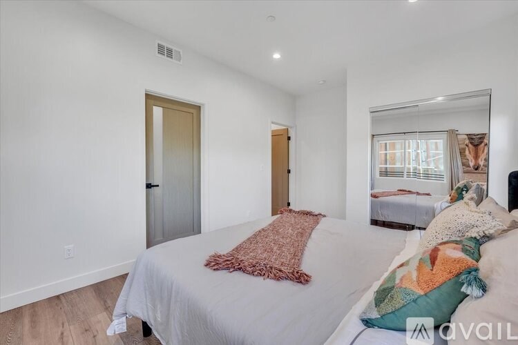 A bedroom with a bed, a mirror, and a window.