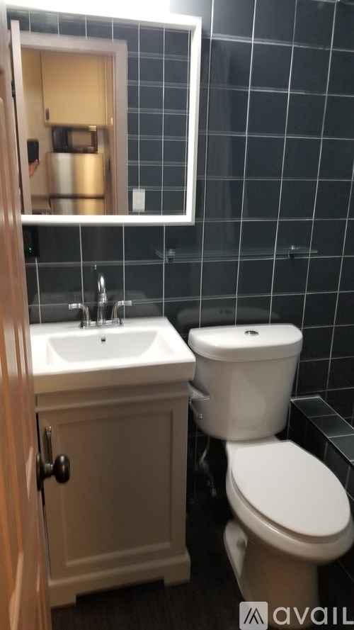 A bathroom with a toilet, sink, and mirror.