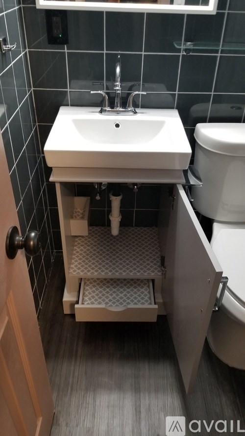 A bathroom with a sink, toilet and a cabinet.