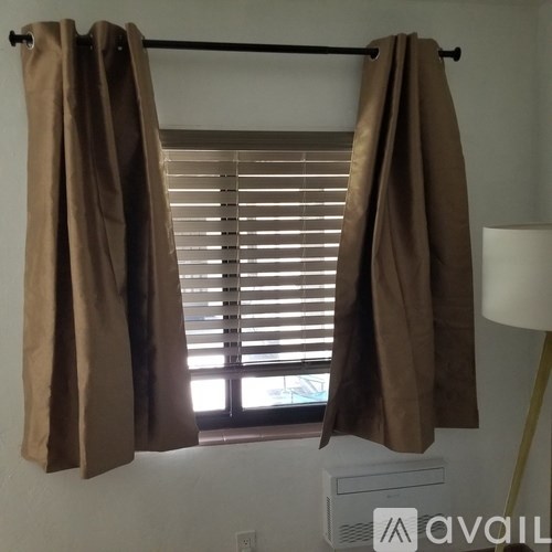 A window with brown curtains and blinds.