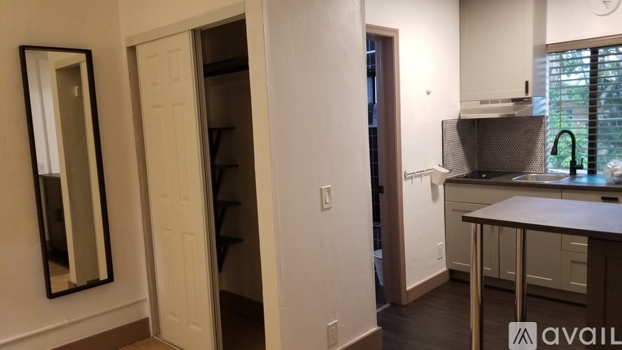 A kitchen area with a sink and a mirror on the wall.