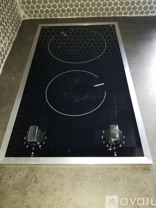 A black induction cooktop with four burners and a control panel.