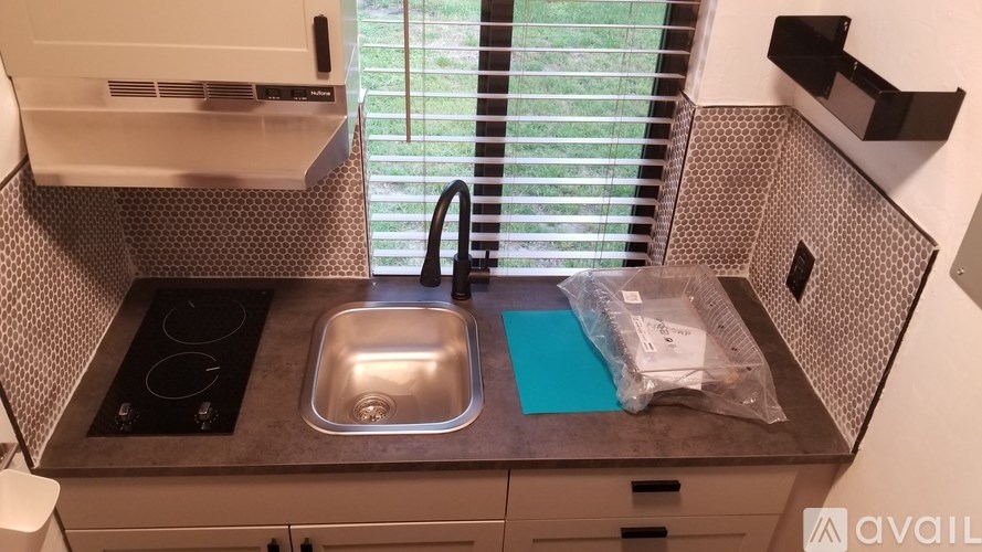A kitchen with a sink and a window with blinds.