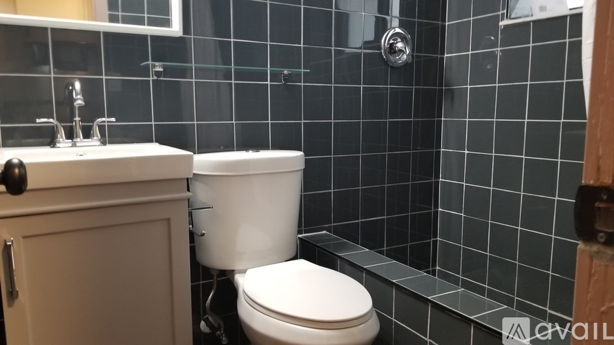 A white toilet is in a bathroom with a black tiled wall.