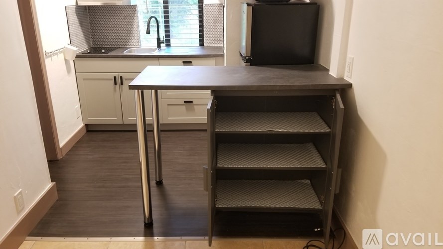 A kitchen with a black countertop and a TV on the wall.