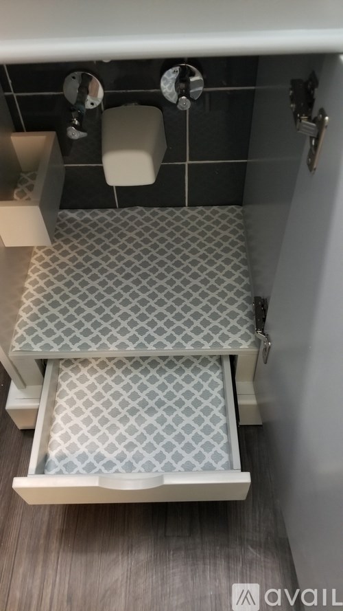 A white toilet with a grey and white tiled floor.
