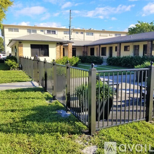 A black metal fence with a gate is in front of a building.