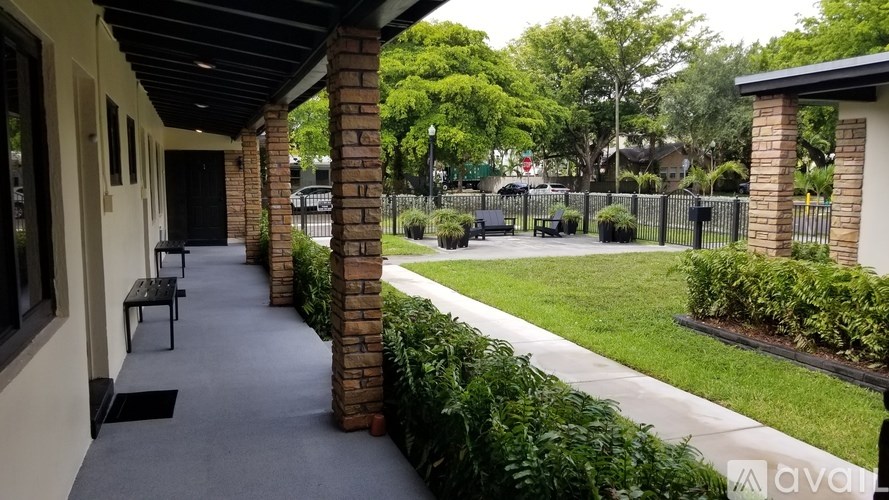 A porch with a grey carpet and a brick pillar.