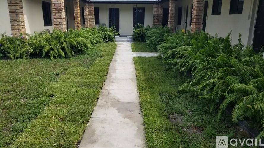 A pathway leads to a building entrance surrounded by greenery.