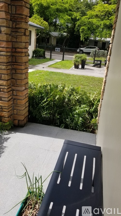 A patio with a bench and a brick pillar.