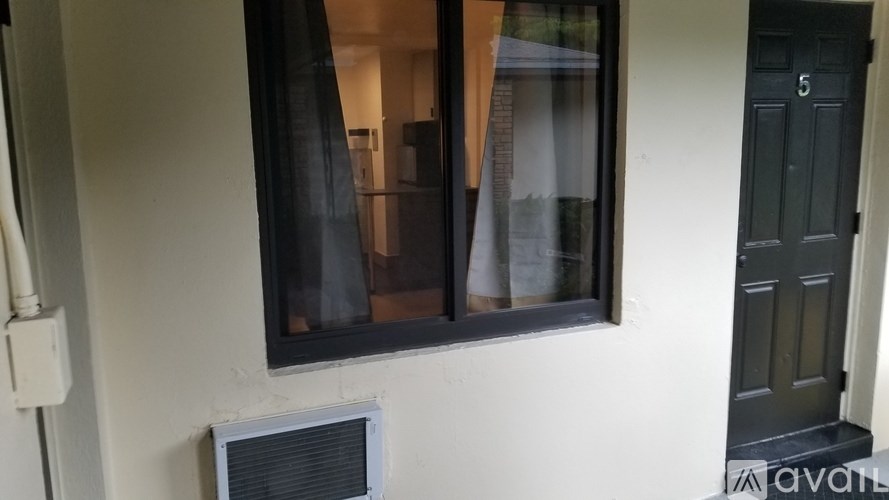 A window with a black frame and a black door with the number 5 on it.