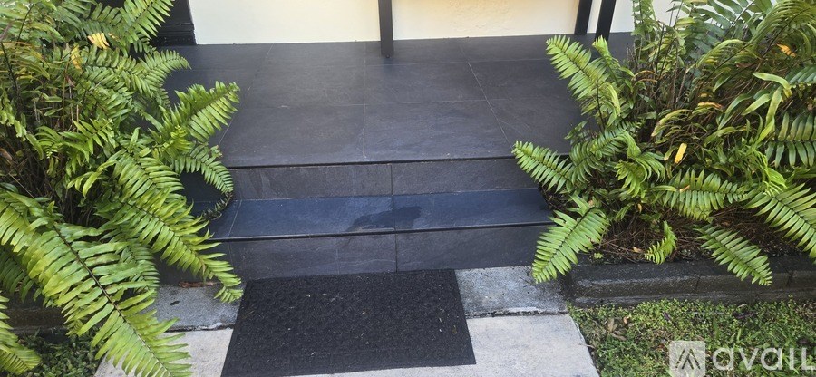 A black mat is on the steps leading to a house.