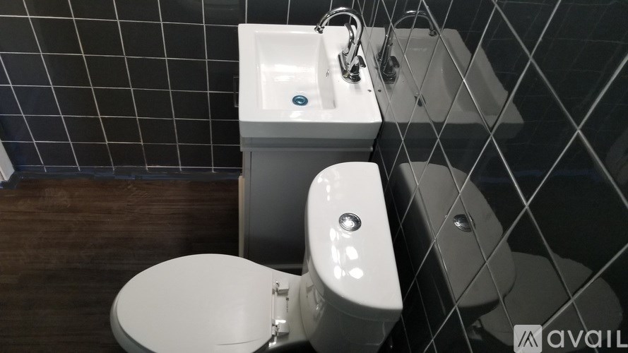 A white toilet with a sink in front of a tiled wall.