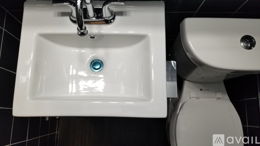 A white sink with a chrome faucet and a toilet in a bathroom.
