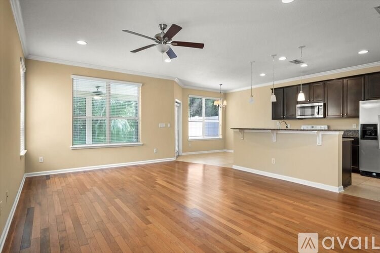 A spacious room with wooden floors and a ceiling fan.