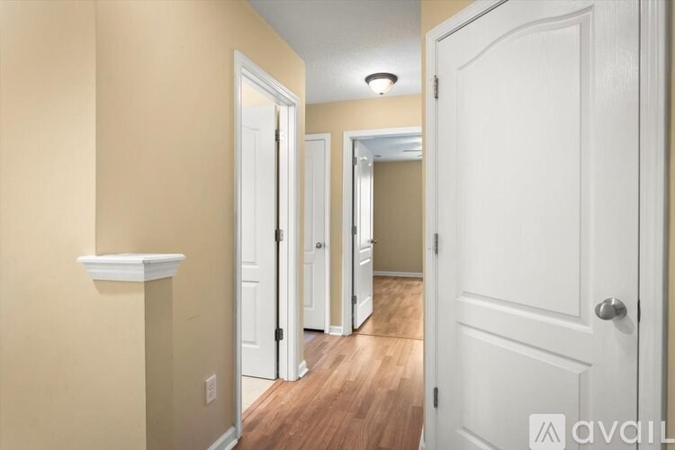 A hallway with three doors and a wooden floor.