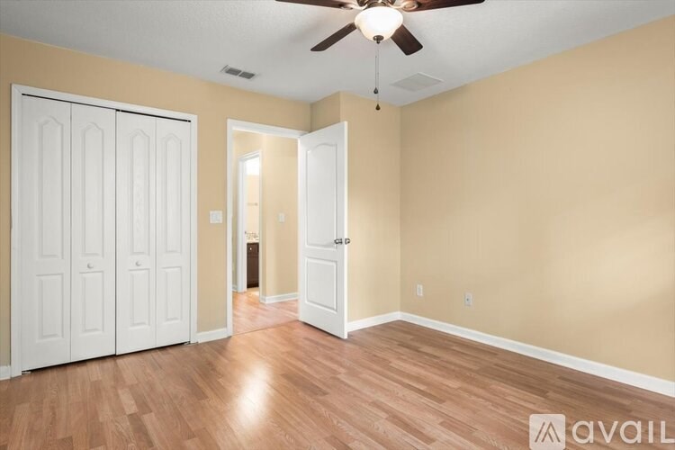 A room with a ceiling fan and wooden flooring.