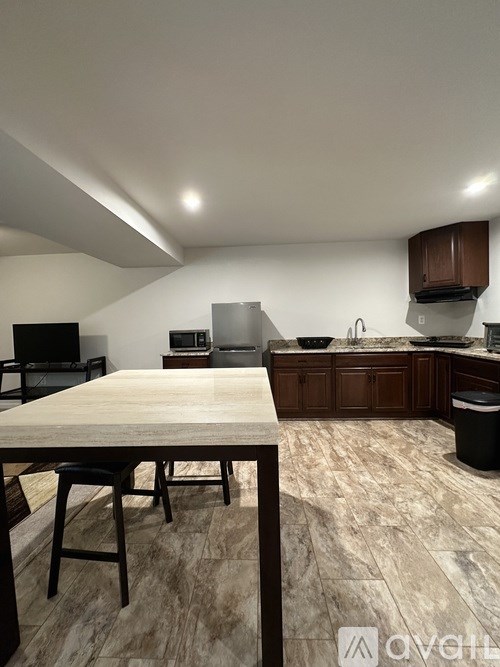 A kitchen with a table and chairs in the foreground and a countertop with a sink and a microwave in the background.
