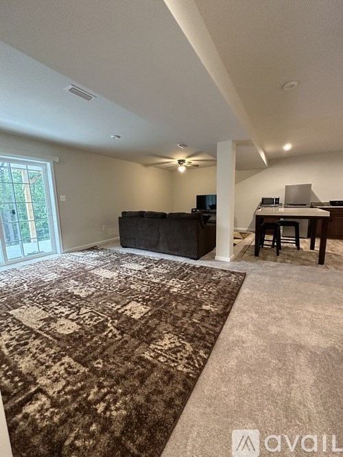 A living room with a rug, a couch, a television, and a desk.