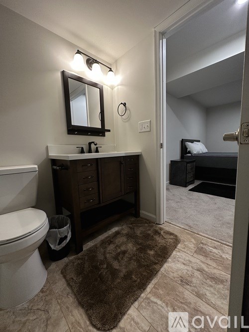 A bathroom with a toilet, sink, and mirror.