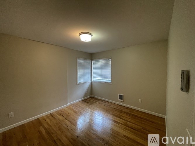 A room with wooden floors and a window with blinds.