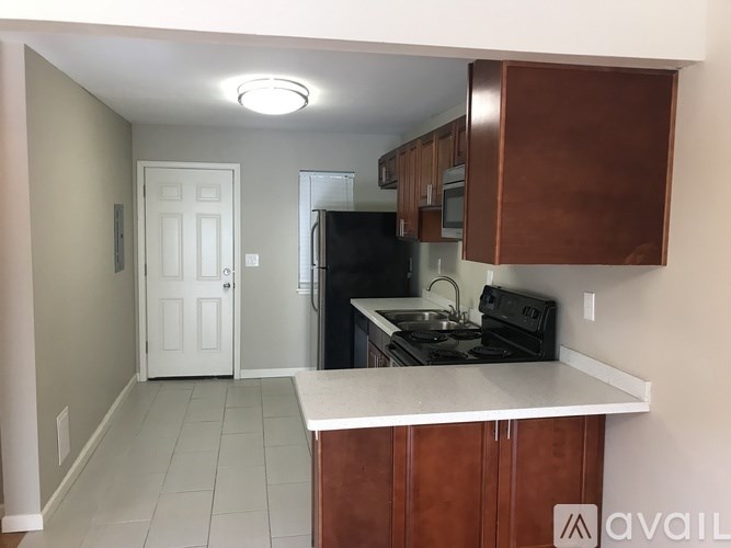 A kitchen with a black fridge and brown cabinets.
