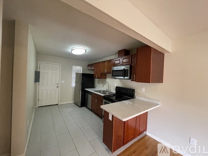 A kitchen with white countertops and wooden cabinets.